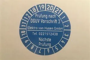 Blauer Prüfaufkleber mit der Aufschrift „Prüfung nach DGUV Vorschrift 3“